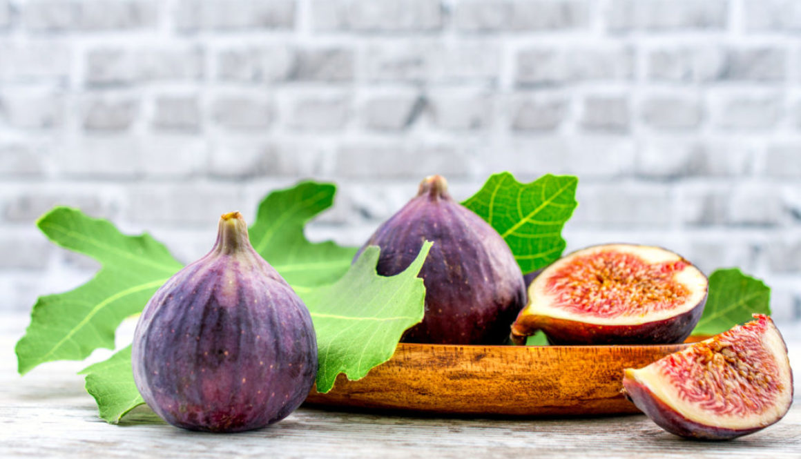 fig fruit on a wooden table with a brick background